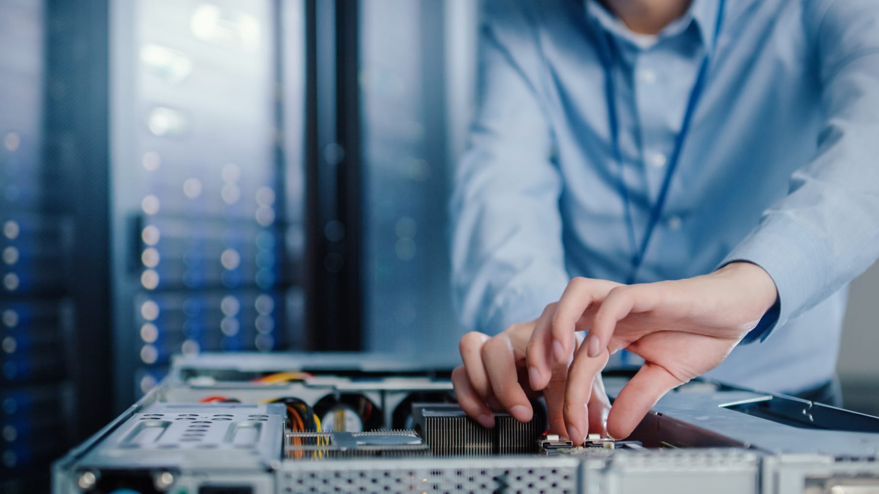 Close-up of hands seating a component inside an open rack server chassis.